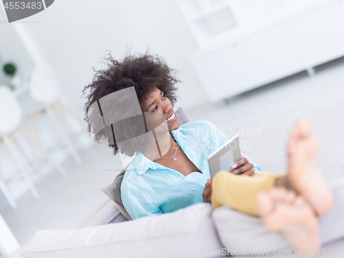 Image of african american woman at home using digital tablet