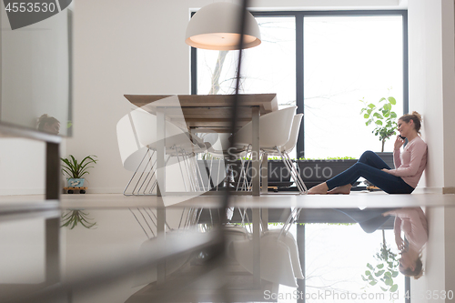 Image of young woman using mobile phone on the floor