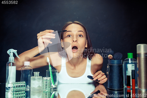 Image of Beauty woman applying makeup. Beautiful girl looking in the mirror and applying cosmetic with a big brush.