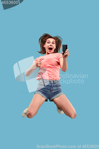 Image of Full length of pretty young woman with mobile phone while jumping