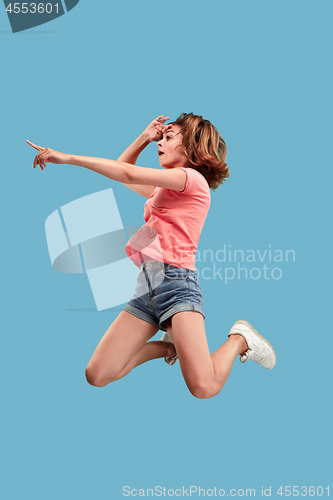 Image of Freedom in moving. Pretty young woman jumping against blue background