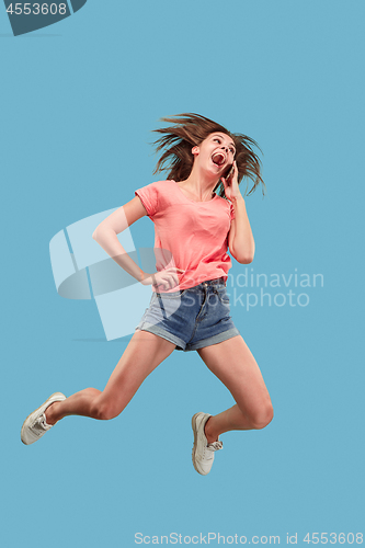 Image of Full length of pretty young woman with mobile phone while jumping