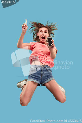 Image of Full length of pretty young woman with mobile phone while jumping