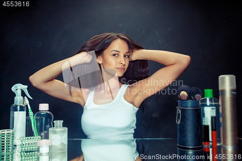 Image of Beauty woman after applying makeup. Beautiful girl looking in the mirror and applying cosmetic with a brush.