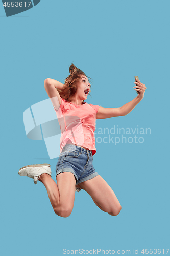 Image of Full length of pretty young woman with mobile phone while jumping