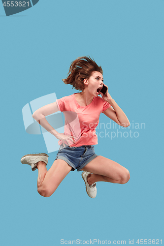 Image of Full length of pretty young woman with mobile phone while jumping