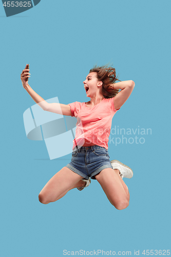 Image of Full length of pretty young woman with mobile phone while jumping