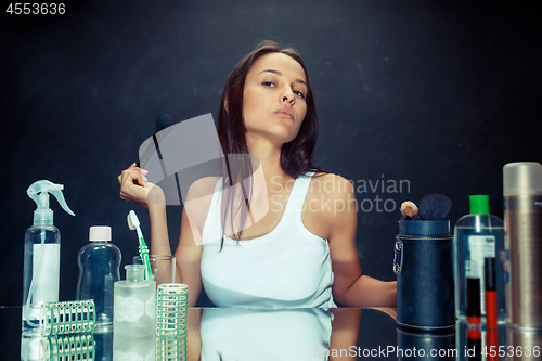 Image of Beauty woman applying makeup. Beautiful girl looking in the mirror and applying cosmetic with a big brush.