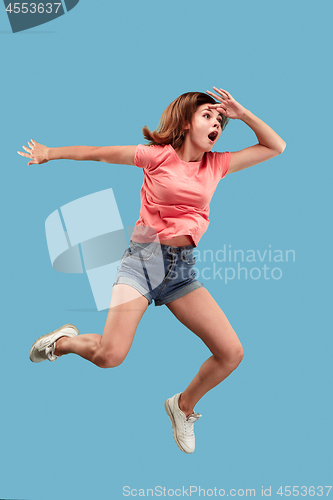 Image of Freedom in moving. Pretty young woman jumping against blue background