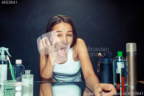 Image of Beauty woman applying makeup. Beautiful girl looking in the mirror and applying cosmetic with a Eyeliner.