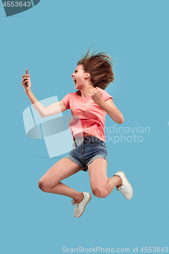 Image of Full length of pretty young woman with mobile phone while jumping