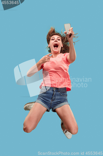 Image of Full length of pretty young woman with mobile phone while jumping