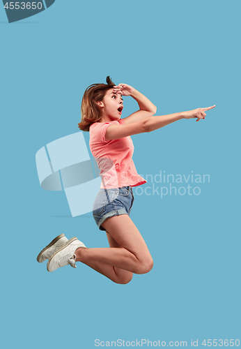 Image of Freedom in moving. Pretty young woman jumping against blue background