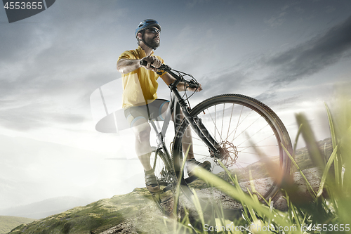 Image of The young fit men in helmet conquering mountains on a bicycle.