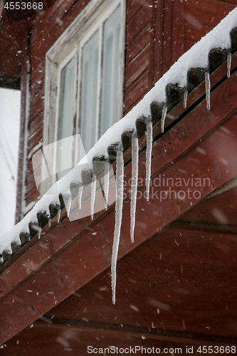 Image of Brown house roof with icicles.