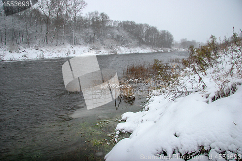 Image of Snow covered landscape with forest and riwer during the winter.