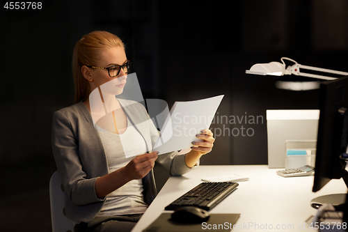 Image of businesswoman with papers working at night office