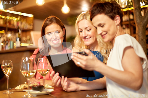 Image of women with tablet pc at wine bar or restaurant