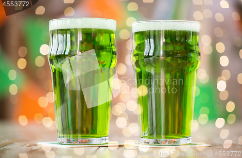 Image of two glasses of green beer on wooden table