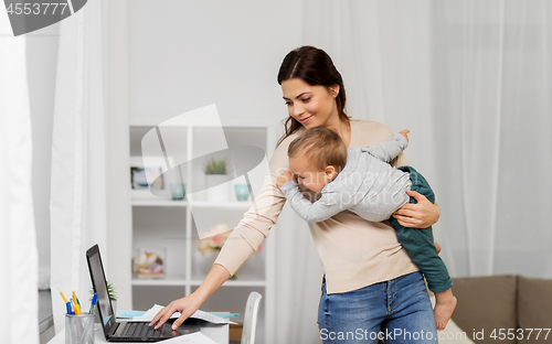 Image of happy mother with baby and laptop working at home