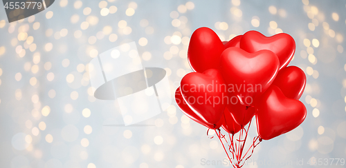 Image of red heart shaped helium balloons on white