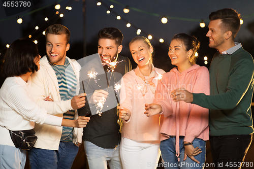 Image of happy friends with sparklers at rooftop party