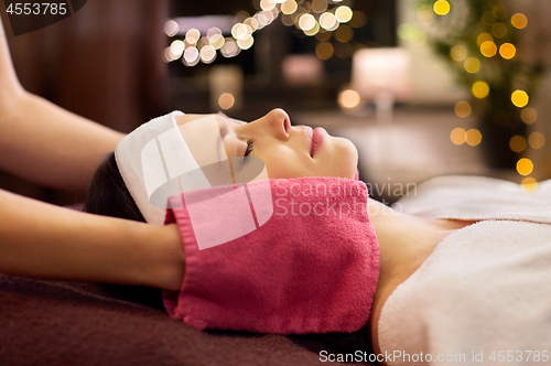 Image of woman having face massage with terry gloves at spa