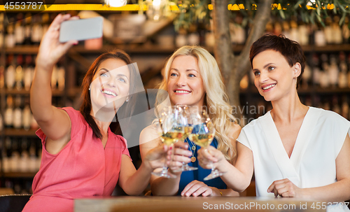 Image of women taking selfie by smartphone at wine bar