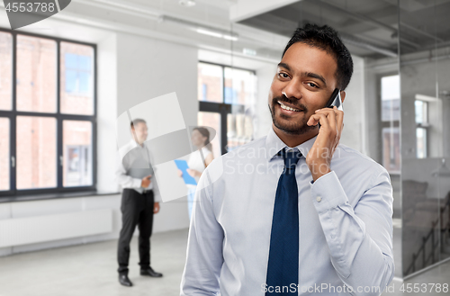 Image of indian businessman calling on smartphone at office