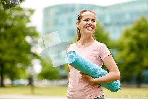 Image of happy smiling woman with exercise mat at city park