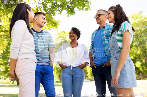 Image of happy international friends talking in park