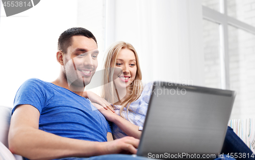 Image of happy couple with laptop computer at home