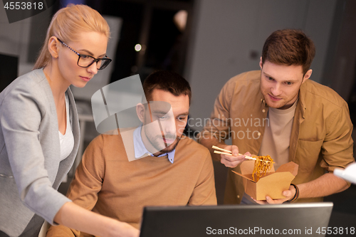 Image of business team with computer working late at office