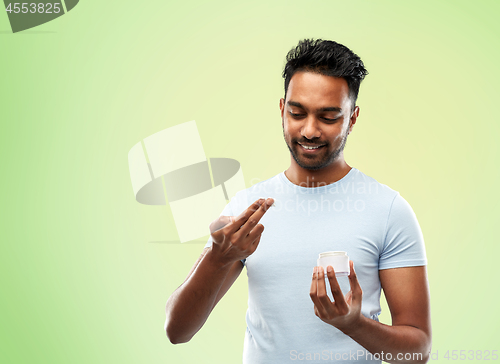 Image of happy indian man applying cream to face