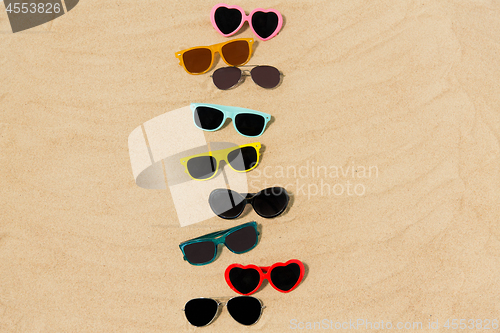 Image of different sunglasses on beach sand