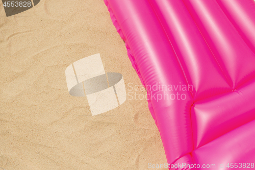 Image of pink swimming mattress on beach