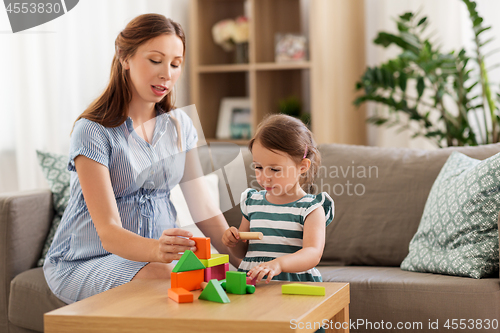 Image of pregnant mother and daughter with toy blocks