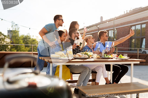 Image of happy friends taking selfie at rooftop party