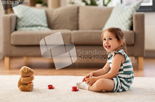 Image of little girl playing with toy tea set at home