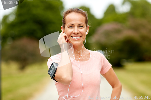 Image of woman with earphones listening to music at park