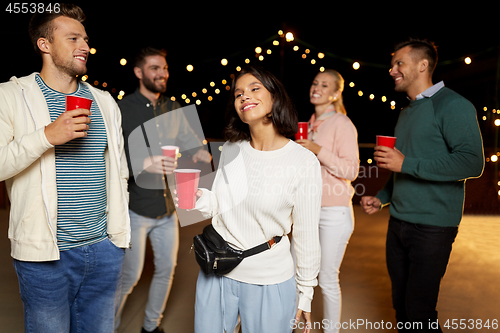 Image of friends with drinks dancing at rooftop party