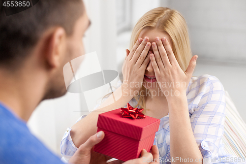 Image of happy couple with gift box at home