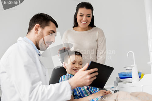 Image of dentist showing tablet pc to kid at dental clinic