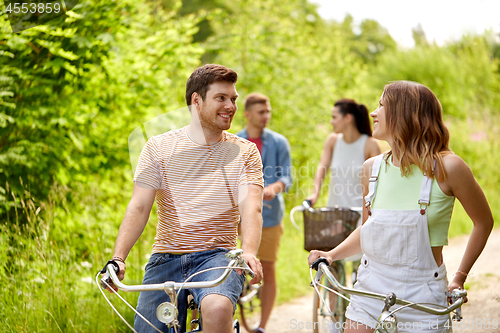 Image of happy friends riding fixed gear bicycles in summer