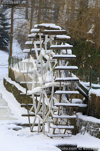 Image of Small waterwheel in frozen creek in park