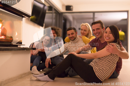 Image of multiethnic couples sitting in front of fireplace