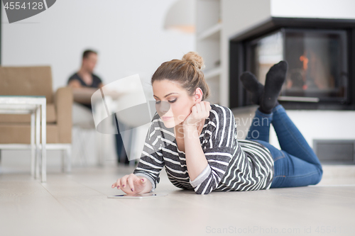 Image of woman using tablet computer in front of fireplace