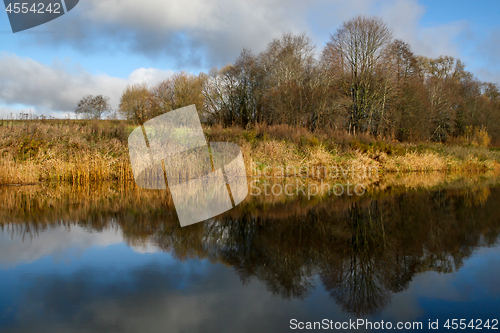 Image of Autumn landscape with colorful trees, yellow grass and river.