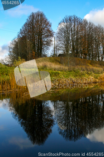 Image of Autumn landscape with colorful trees, yellow grass and river. Re