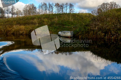 Image of Autumn landscape with trees grass and boat in river. 